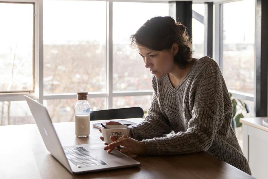 Woman sat at her dining table using a Macbook.